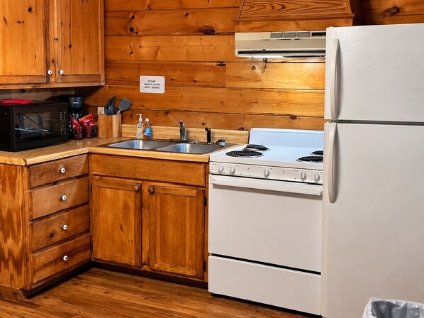 A kitchen with wooden cabinets, a microwave, a stove, and a refrigerator.
