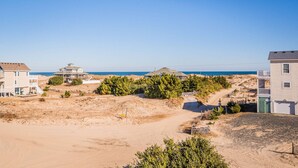 Zona residencial a la costa, amb cases, terreny sorrenc i vista clara de l'oceà.