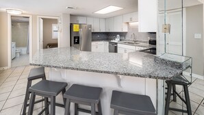A modern kitchen with a granite countertop, white cabinets, and a built-in dishwasher. - Nautilus 2311  Gulf View 2BD/2BA 3rd Floor.  Free Beach Service 3/1-10/31 (Fort Walton Beach)