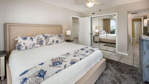 A bedroom with a large bed, a ceiling fan, a nightstand, a dresser, and a walk-in closet. - Nautilus 2311  Gulf View 2BD/2BA 3rd Floor.  Free Beach Service 3/1-10/31 (Fort Walton Beach)