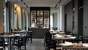 A restaurant with a bar area, tables, chairs, and a bartender. - Hotel Windsor (Laigueglia)