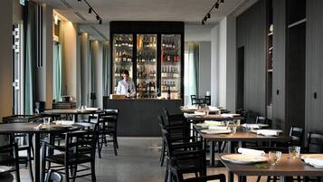 A restaurant with a bar area, tables, chairs, and a bartender.