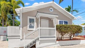 Una casa de un piso con porche, una pequeña escalera y valla blanca.