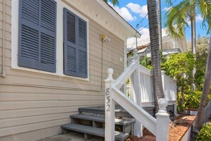 A house with a white exterior, dark shutters, a white porch railing, and a number 832 on the post.