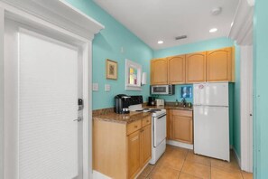 A compact kitchen with a white refrigerator, a microwave, and a stove.
