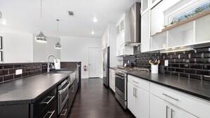 Cocina moderna con una isla central, electrodomésticos de acero inoxidable y muebles de cocina en blanco y negro.