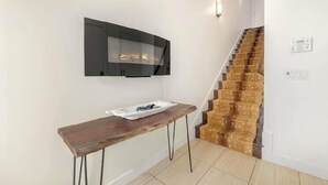 Un interior moderno con una mesa de madera, chimenea empotrada y una escalera.