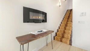 Una escalera con alfombra estampada, un banco de madera y una chimenea adosada a la pared.