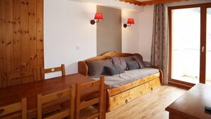 A wooden interior with a sofa bed, a dining table, chairs, and two wall-mounted lamps. - Ski-in/ski-out & foot of the slopes, 1st floor, view ski slopes, swimming pool, sauna, balcony, tv (Les Orres)