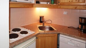A compact kitchen with a stove, sink, and dishwasher. - Ski-in/ski-out & foot of the slopes, 1st floor, view ski slopes, swimming pool, sauna, balcony, tv (Les Orres)