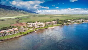Un hôtel situé sur la côte, composé de plusieurs bâtiments, avec une plage et un paysage montagneux en arrière-plan.