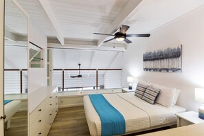 A bedroom with a bed, a nightstand, a ceiling fan, a window with blinds, and a painting on the wall. - Oceanfront Maui condo with whale watching views, hot tub summer deals (Wailuku)