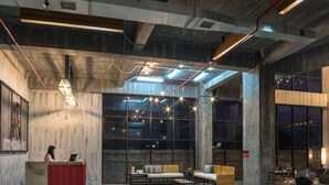 Un vestíbulo amplio con mostrador de recepción, zona de estar y ventanas grandes.