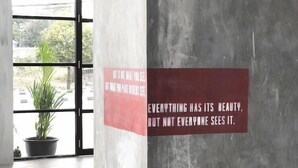 Un interior moderno con una pared de concreto y una ventana que muestra una planta afuera.