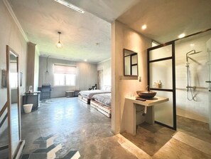 Une chambre spacieuse avec un grand lit, un petit bureau et une salle de bain moderne dotée d’une douche en verre.