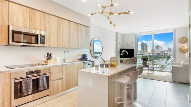 A modern kitchen with a central island, stainless steel appliances, and a large window offering a city view. - One Bedroom Condo King Bed With City Views (Miami)