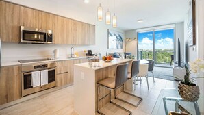 A modern kitchen with a built-in microwave, oven, and bar area with seating. - One Bedroom Condo King Bed With City Views (Miami)