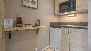 Une petite cuisine équipée d’un four à micro-ondes, d’un grille-pain et d’une bouilloire, le tout posé sur une étagère en bois.