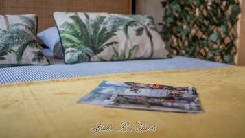 A bed with a yellow blanket and two pillows with a tropical leaf pattern.