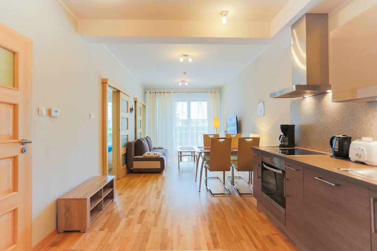 Een moderne keuken met een eethoek, houten vloeren en inbouwapparatuur.