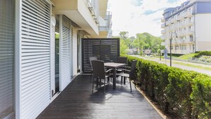 A balcony with a table and chairs, a view of the street, and a hedge. - Apartamenty Swinoujscie - Casa Marina (Swinoujscie)