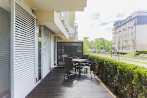 A balcony with a table and chairs, a view of the street, and a hedge. - Apartamenty Swinoujscie - Casa Marina (Swinoujscie)