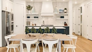 Una cocina moderna con armarios blancos, una isla central, luces colgantes y un salpicadero de baldosas en espiga.