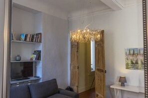 Una sala de estar con una estantería, un televisor, un sofá, una lámpara y una puerta de madera.
