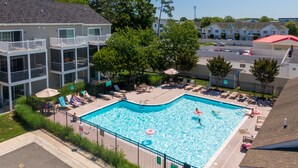 Una piscina con sillas de descanso y sombrillas, rodeada de edificios de apartamentos.