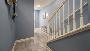 Una escalera con balaustres blancos, una pared azul claro y una puerta blanca al final.