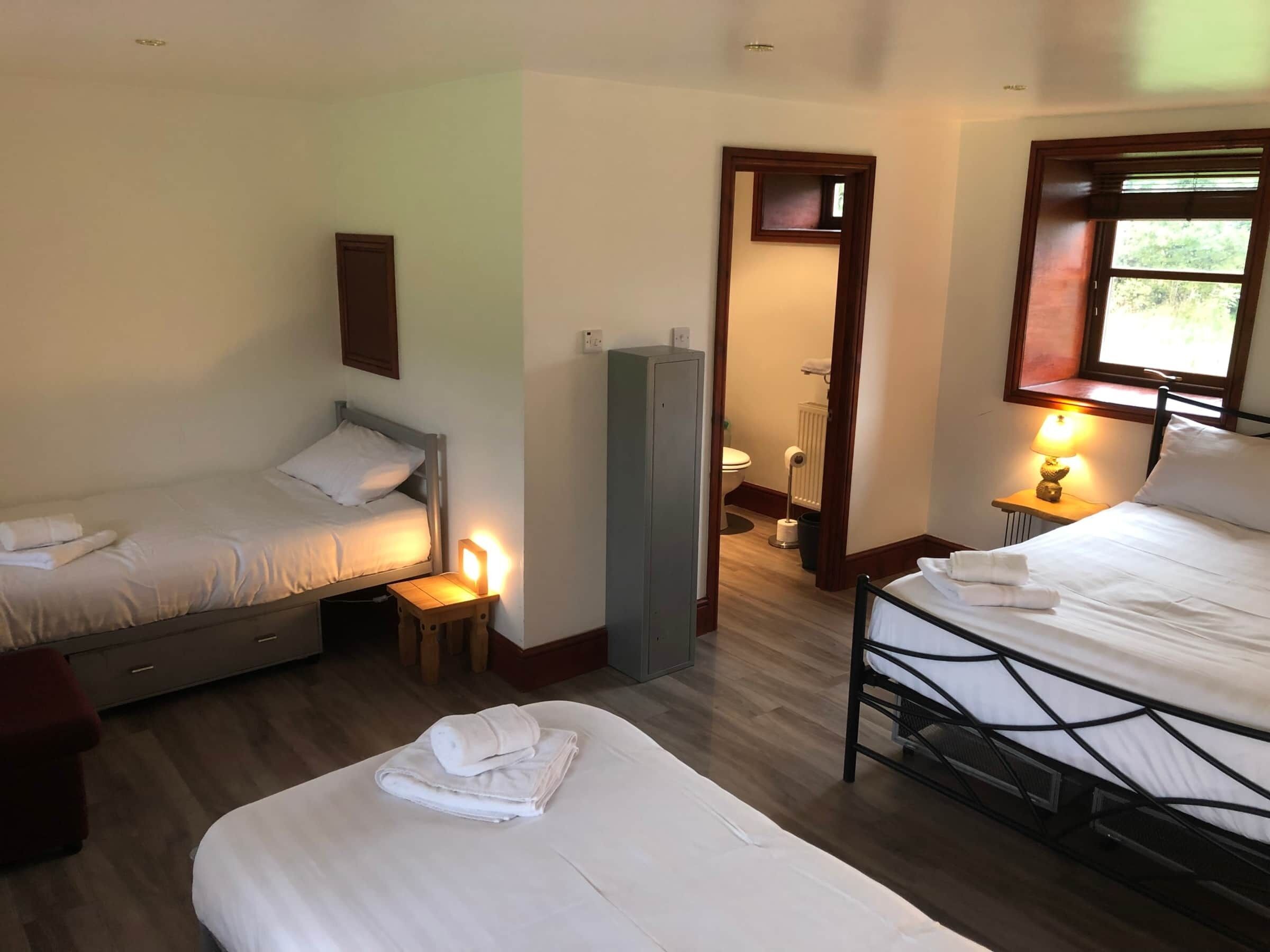 Ein Hotelzimmer mit zwei Betten, einem kleinen Tisch, einem Heizkörper und einem Fenster mit Blick.