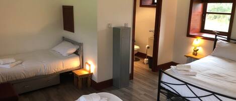 Ein Hotelzimmer mit zwei Betten, einem kleinen Tisch, einem Heizkörper und einem Fenster mit Blick.
