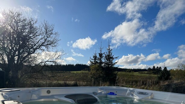 A hot tub with a clear view of a natural landscape in the background. - Ochiltree Cottage, Waterside Newton Stewart. (Polbae)