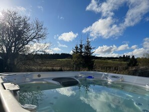 Ett bubbelbad med fri utsikt över ett vackert naturlandskap i bakgrunden.