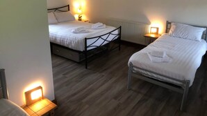 A hotel room with two beds, wooden flooring, and bedside lamps. - Ochiltree Cottage, Waterside Newton Stewart. (Polbae)