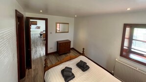 A bedroom with a wooden bed, a dresser, a mirror, and a radiator. - Maberry Cottage, Waterside Newton Stewart. (Polbae)