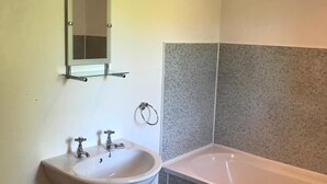 A bathroom with a pedestal sink, a mirror, a towel rack, and a bathtub. - Maberry Cottage, Waterside Newton Stewart. (Polbae)