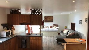 A compact living space with a kitchenette, a dining area, and a bedroom. - Maberry Cottage, Waterside Newton Stewart. (Polbae)