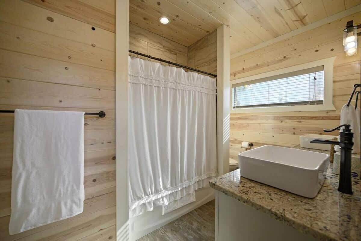 A wooden interior with a shower, a sink, and a window.