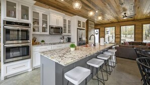 A modern kitchen with white cabinetry, stainless steel appliances, and a granite island with bar stools.