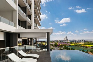 Ein modernes Hotel mit einem Dachpool, einer Glasbrüstung und Blick auf die Stadt.