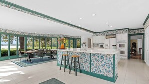 A spacious kitchen with a large island, white cabinets, and a view of the outdoors.