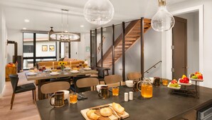 Un espace repas moderne doté d’un grand îlot central, de sièges et d’un escalier.
