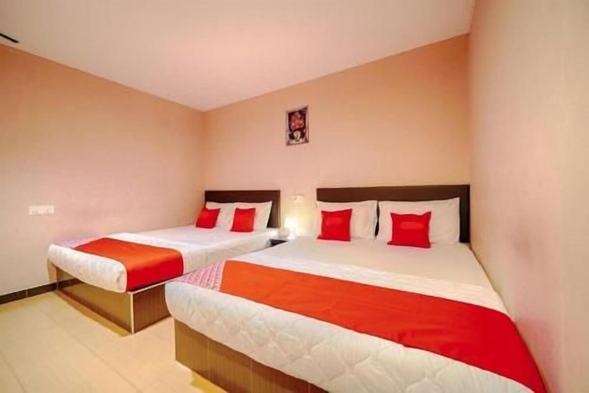 A hotel room with two beds, each with a red blanket and white bedding.