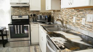 A kitchen with stainless steel appliances, a microwave, and a tiled backsplash. - Charming 4BR Historic Home near Downtown & Duke, Spacious & Stylish (Durham)