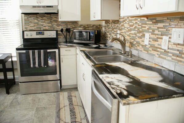 A kitchen with stainless steel appliances, a microwave, and a tiled backsplash.
