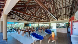 Un espace intérieur spacieux, doté de tables et de chaises en bois, d’un comptoir d’accueil et de grandes fenêtres offrant une vue sur l’extérieur.