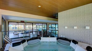 Un espace spa comprenant un bain à remous, des sièges et une vue sur la terrasse extérieure.