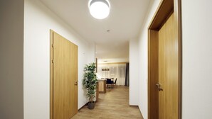 Un couloir avec des portes en bois, une plante en pot et, au fond, un coin repas.