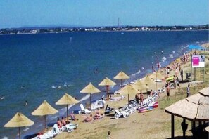 Uma praia com guarda-sóis, espreguiçadeiras e vista para o mar.